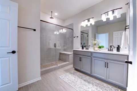 a bathroom with a double vanity sink mirror and shower