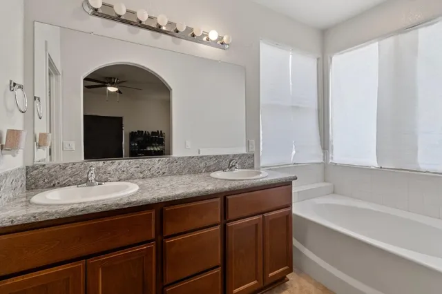 a bathroom with a granite countertop bathtub sink and mirror