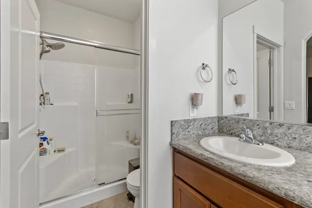 a bathroom with a granite countertop sink a toilet and shower