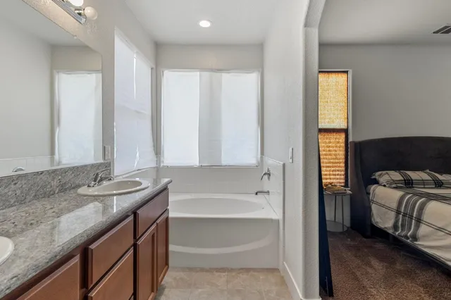 a bathroom with a granite countertop sink and a bathtub