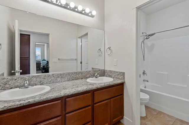 a bathroom with a granite countertop sink double mirror and a bathtub