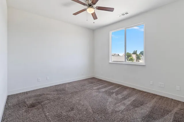 an empty room with a ceiling fan and window