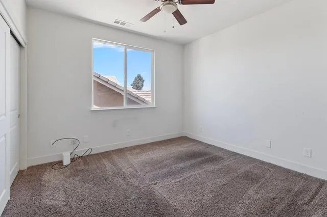 an empty room with a window and a ceiling fan