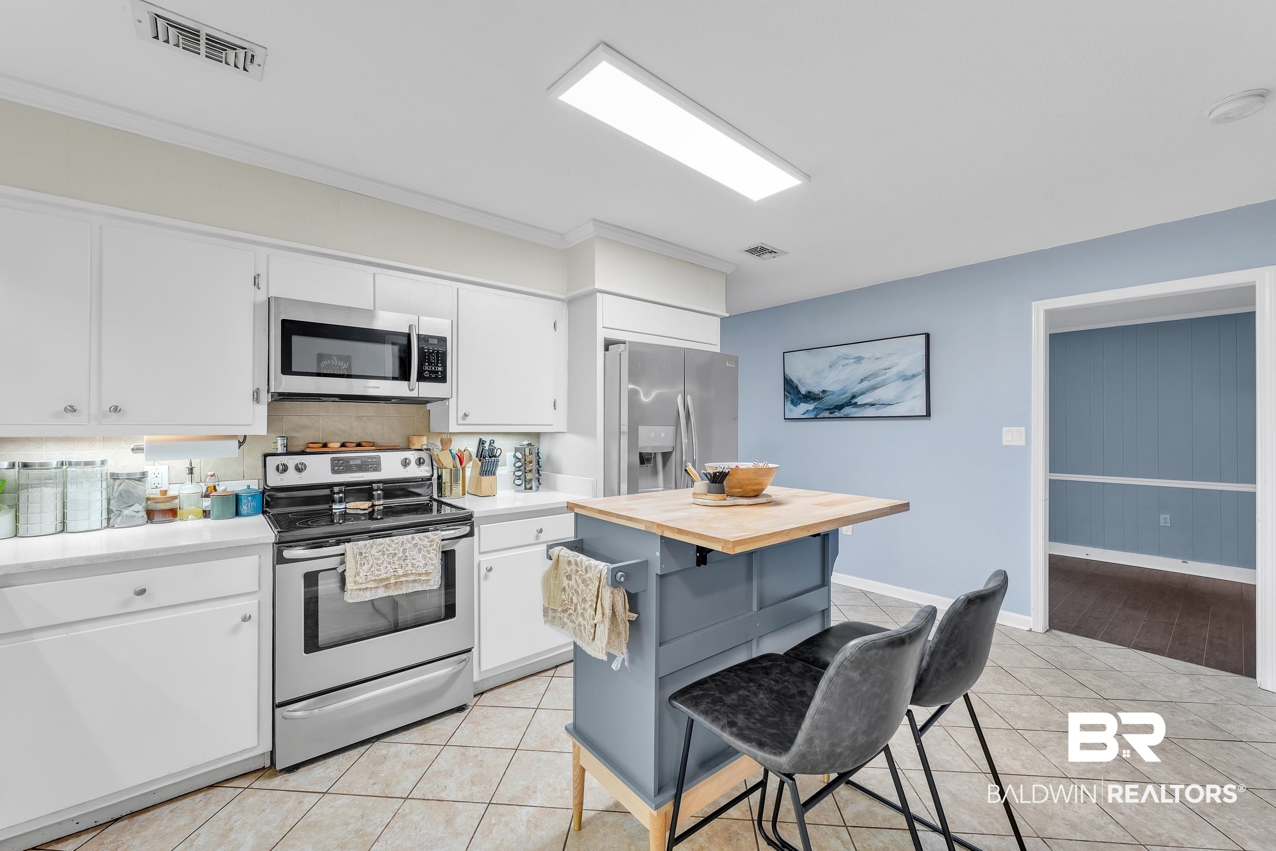 206 West Jackson Avenue Summerdale, AL 36580 - Photo 14 of 37 Kitchen with stainless steel appliances, white cabinets, a breakfast bar, backsplash, and light tile patterned floors