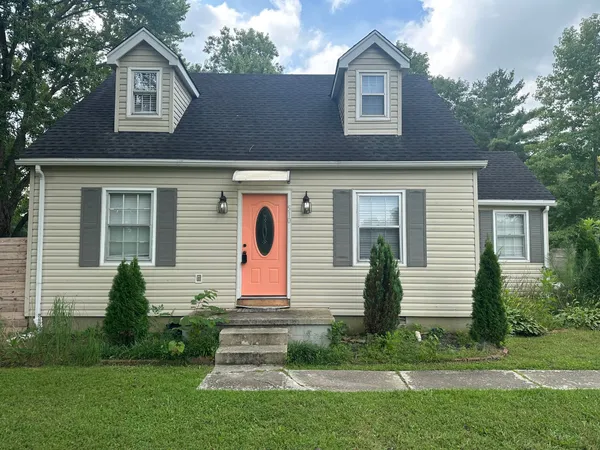 a view of a house with a small yard and a large tree