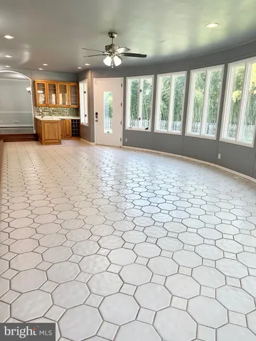 a view of an empty room with kitchen and a window