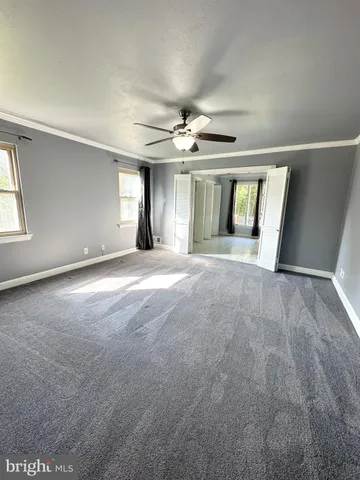 an empty room with windows and chandelier fan