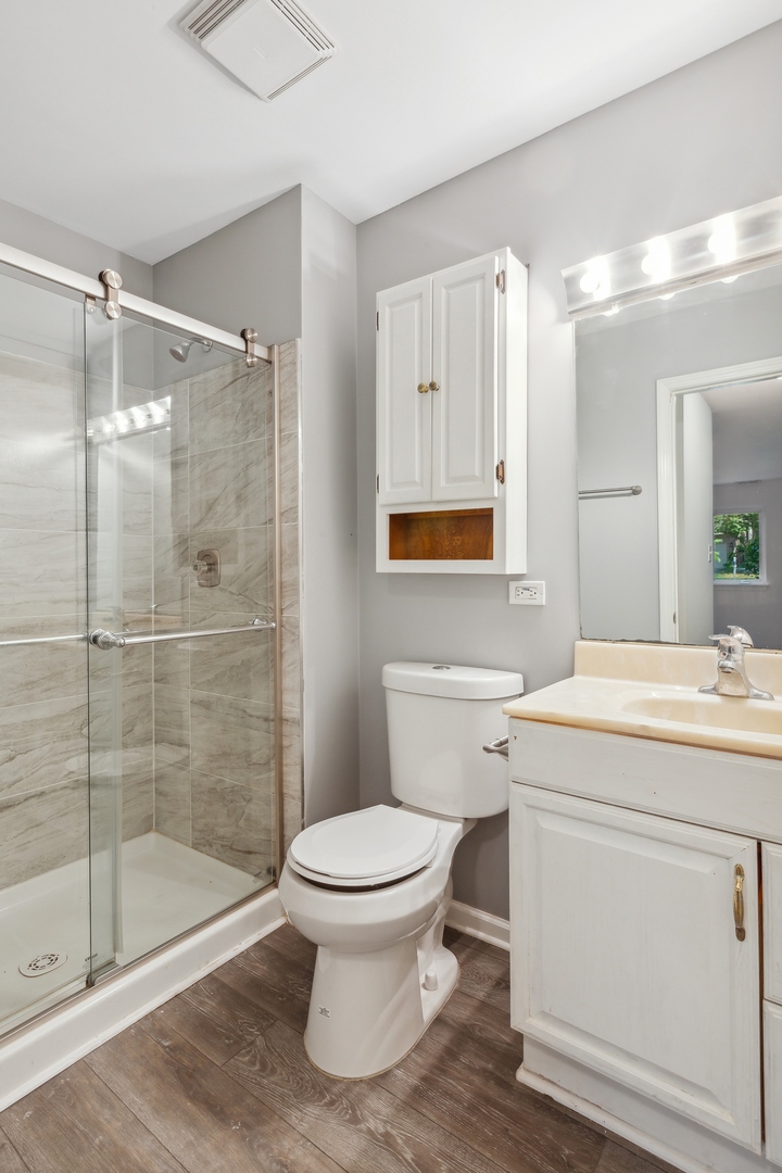 1464 Stonebridge Circle, Unit E2 Wheaton, IL 60189 - Photo 8 of 14 a bathroom with a granite countertop toilet a sink and shower