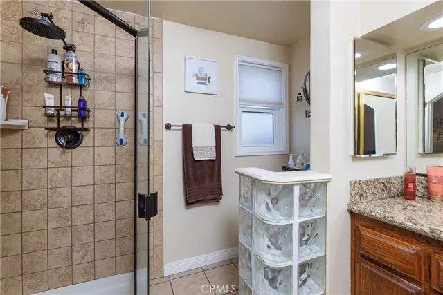 a bathroom with a granite countertop shower a sink and a mirror