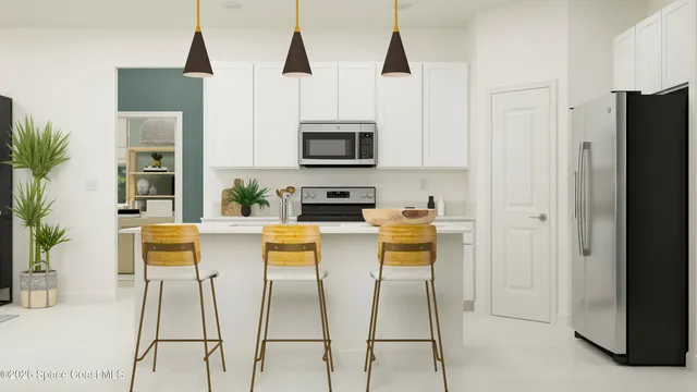 a kitchen with stainless steel appliances kitchen island granite countertop a refrigerator a stove a microwave oven with white cabinets and wooden floor