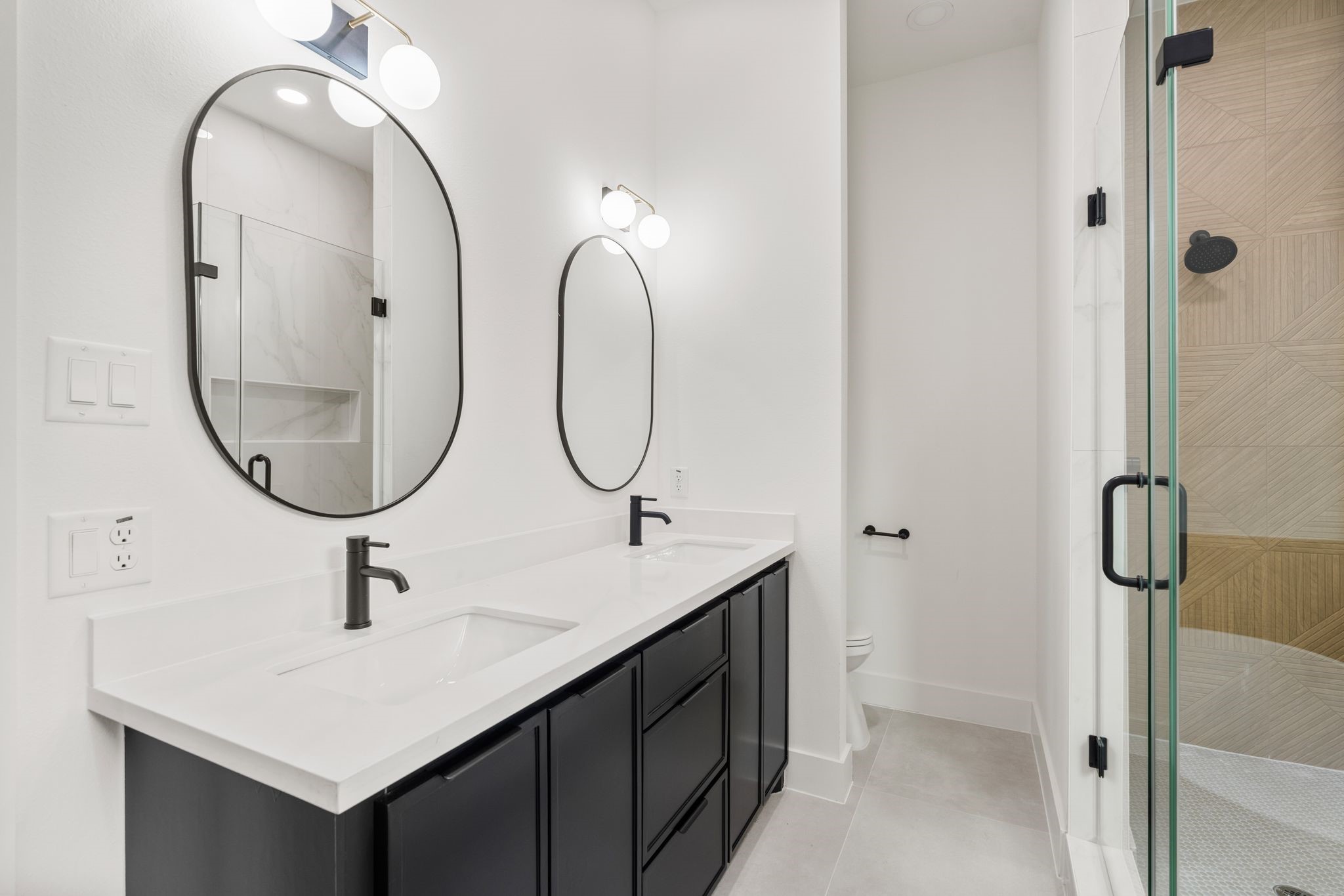 7321 Laura Koppe Road Houston, TX 77028 - Photo 36 of 41 Elegant bathroom featuring a modern double
vanity with sleek black fixtures, oval mirrors, and a
glass-enclosed shower.
