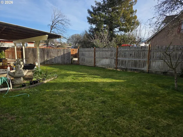 a view of a backyard with table and chairs under an umbrella