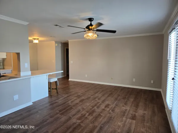 a view of an empty room with window and wooden floor