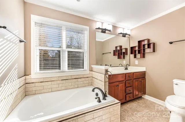 a bathroom with a bathtub sink vanity mirror and toilet