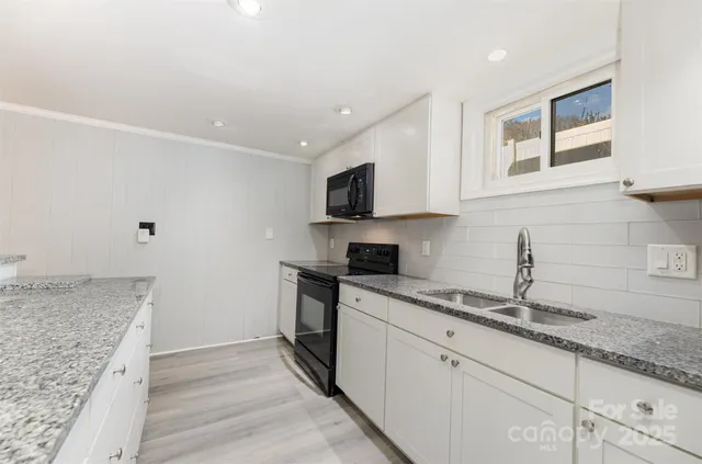a kitchen with granite countertop white cabinets and stainless steel appliances