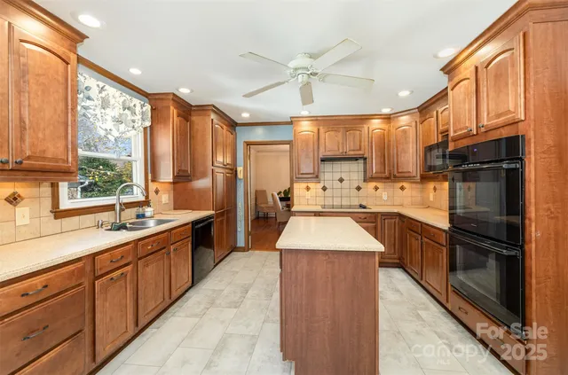 a large kitchen with stainless steel appliances kitchen island granite countertop a sink counter space cabinets and a large window