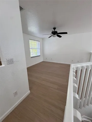 a view of a kitchen and an empty room with wooden floor and a window