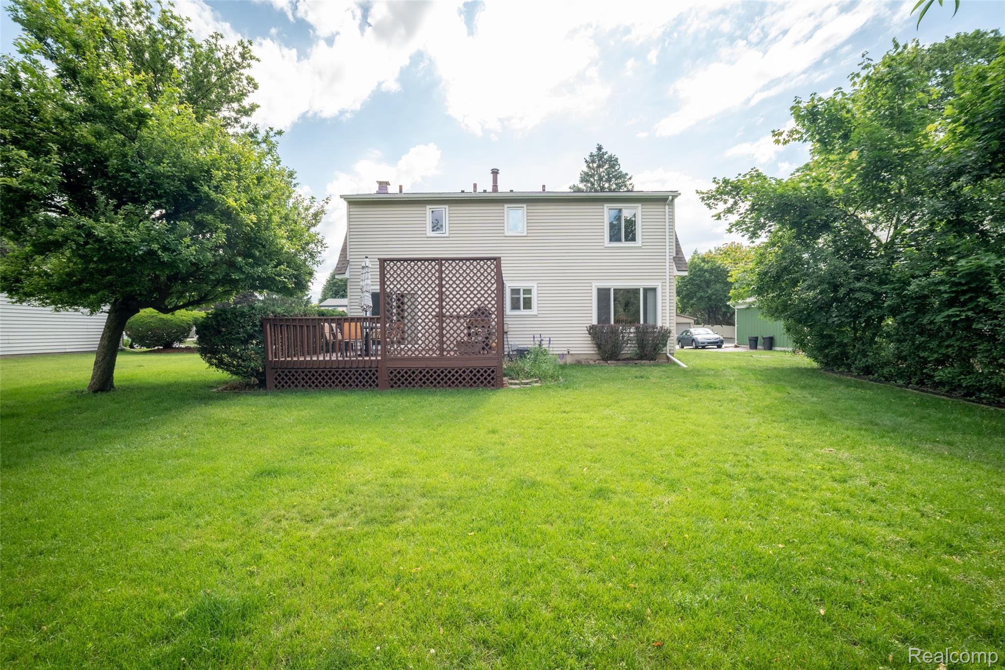 22533 Winfield Road Novi, MI 48375 - Photo 31 of 43 Spacious backyard featuring a multi-level wood deck with lattice screening, ample green space, mature trees, and tan siding