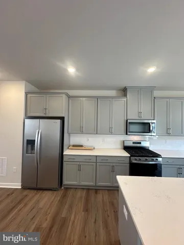 a large kitchen with stainless steel appliances kitchen island granite countertop a stove a refrigerator a sink a dining table and chairs