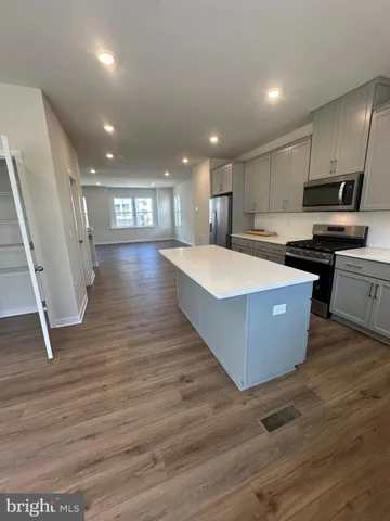 a view of kitchen and empty room with wooden floor