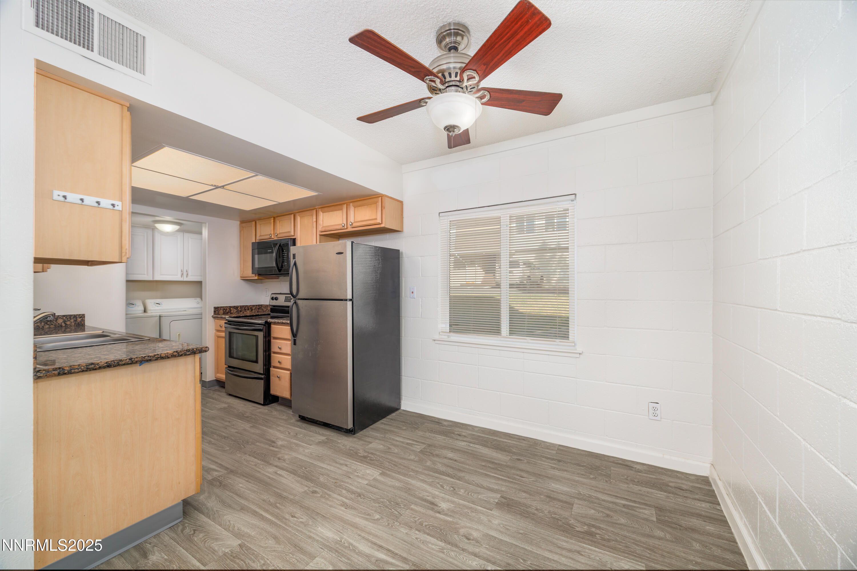 140 Griswold Way, Unit C Reno, NV 89503 - Photo 3 of 17 a kitchen with stainless steel appliances granite countertop a refrigerator a sink dishwasher a stove and a dining table with wooden floor