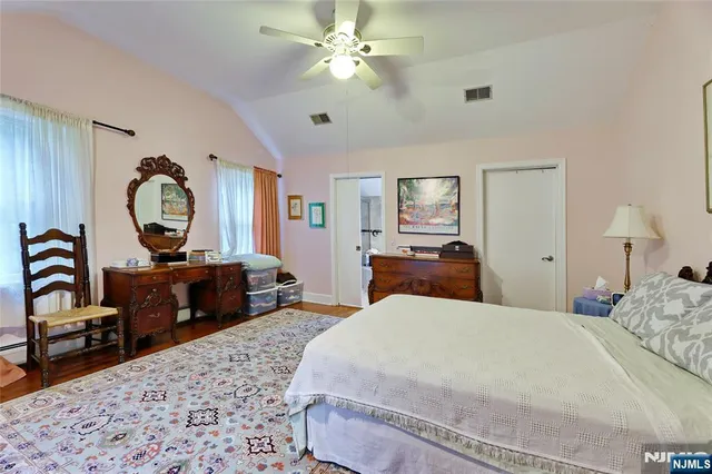 a spacious bedroom with a bed and wooden floor
