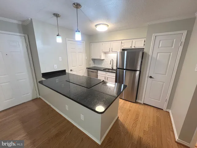 a kitchen with stainless steel appliances granite countertop a refrigerator a sink a stove a dining table and chairs