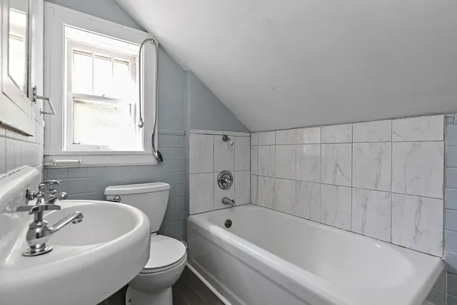 a white bath tub sitting next to a white sink and a toilet