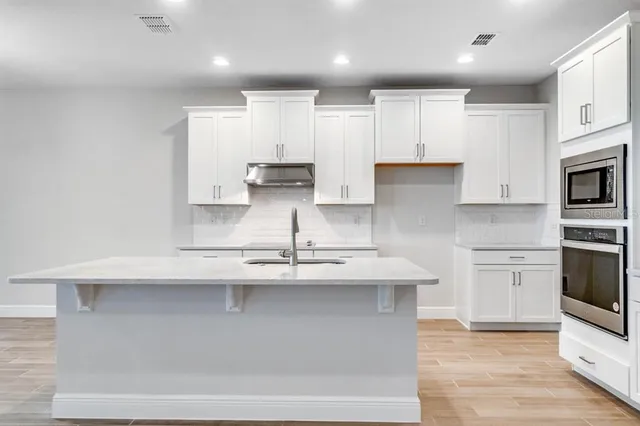 a kitchen with kitchen island white cabinets and stainless steel appliances