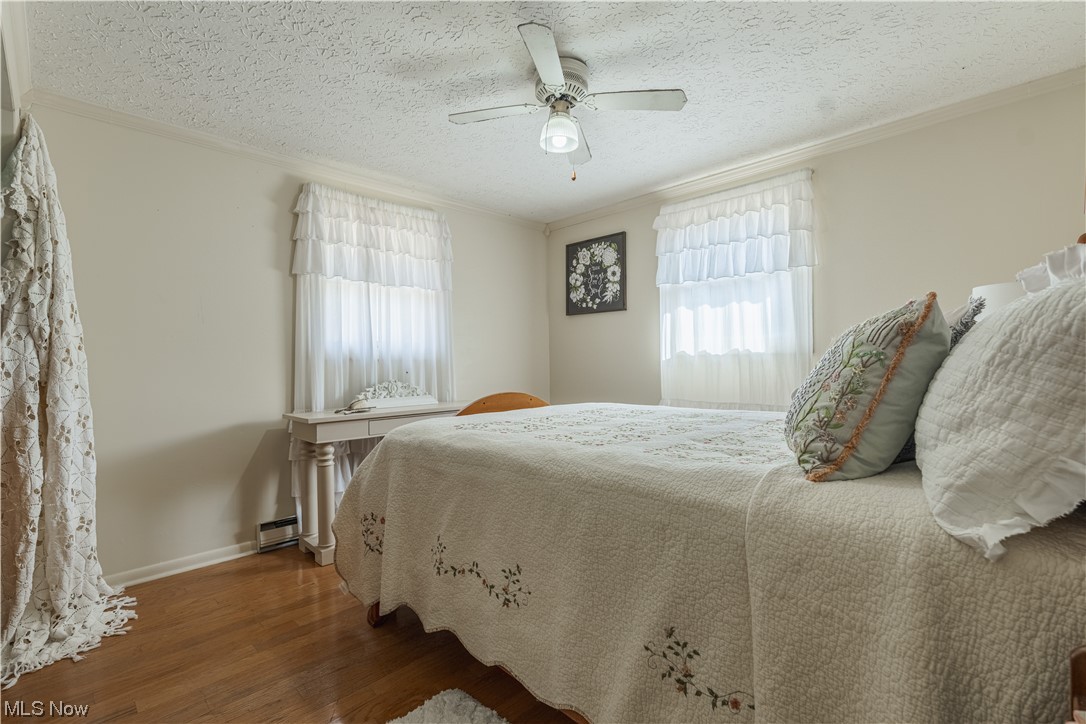 10450 Gavers Road Hanoverton, OH 44423 - Photo 27 of 50 Bedroom featuring multiple windows, dark wood-type flooring, ceiling fan, and a textured ceiling