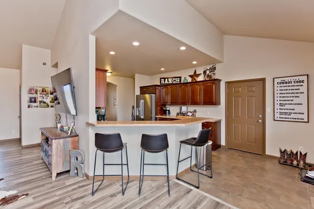 a kitchen with stainless steel appliances kitchen island granite countertop a table chairs in it and wooden floors
