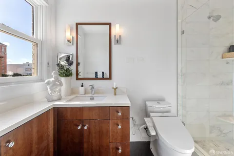 a bathroom with a sink a toilet a mirror and shower