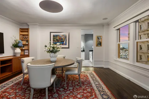 a dining room with wooden floor and large windows