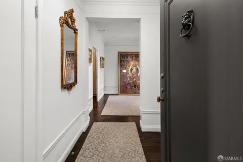 a hallway with white doors wooden floor and front door