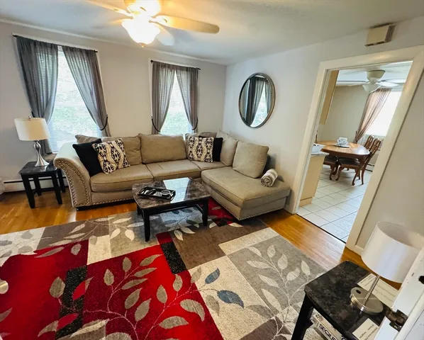 a living room with furniture a mirror and wooden floor