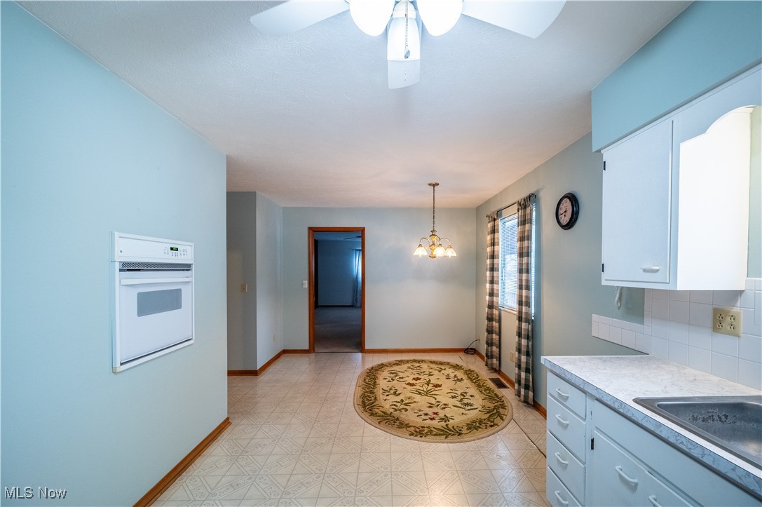 1329 Oak Grove Road Waverly, WV 26184 - Photo 10 of 29 Kitchen with light floors, light countertops, white oven, pendant lighting, and white cabinetry