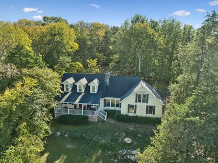 a front view of a house with a yard and large trees
