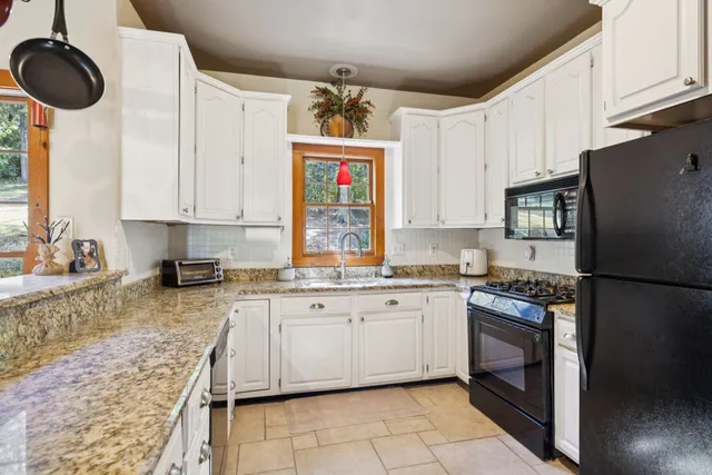 a view of a kitchen with stainless steel appliances granite countertop a sink and a wooden floor