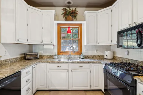a view of a kitchen with stainless steel appliances granite countertop a sink and a wooden floor