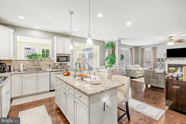 a kitchen with stainless steel appliances granite countertop a refrigerator a stove a sink a dining table and chairs with wooden floor