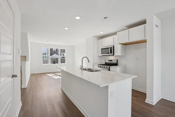 a view of a kitchen with kitchen island a sink wooden floor and a refrigerator