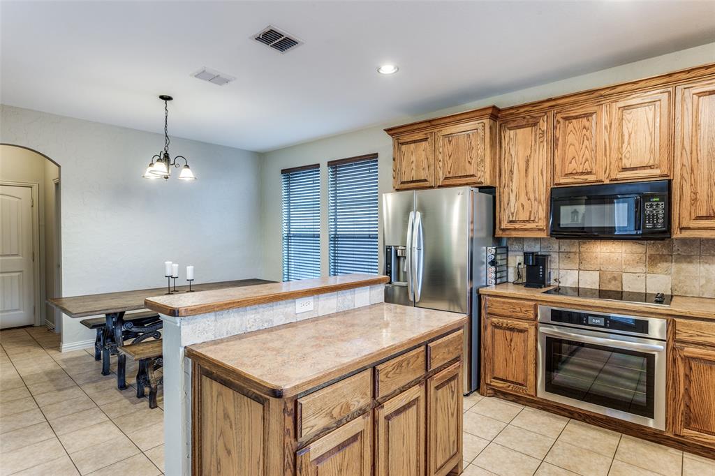 400 Commonwealth Drive Saginaw, TX 76179 - Photo 11 of 32 a kitchen with kitchen island granite countertop a stove refrigerator and microwave
