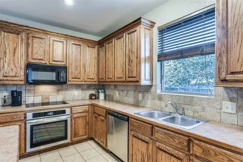 a kitchen with granite countertop a sink a window stainless steel appliances and cabinets