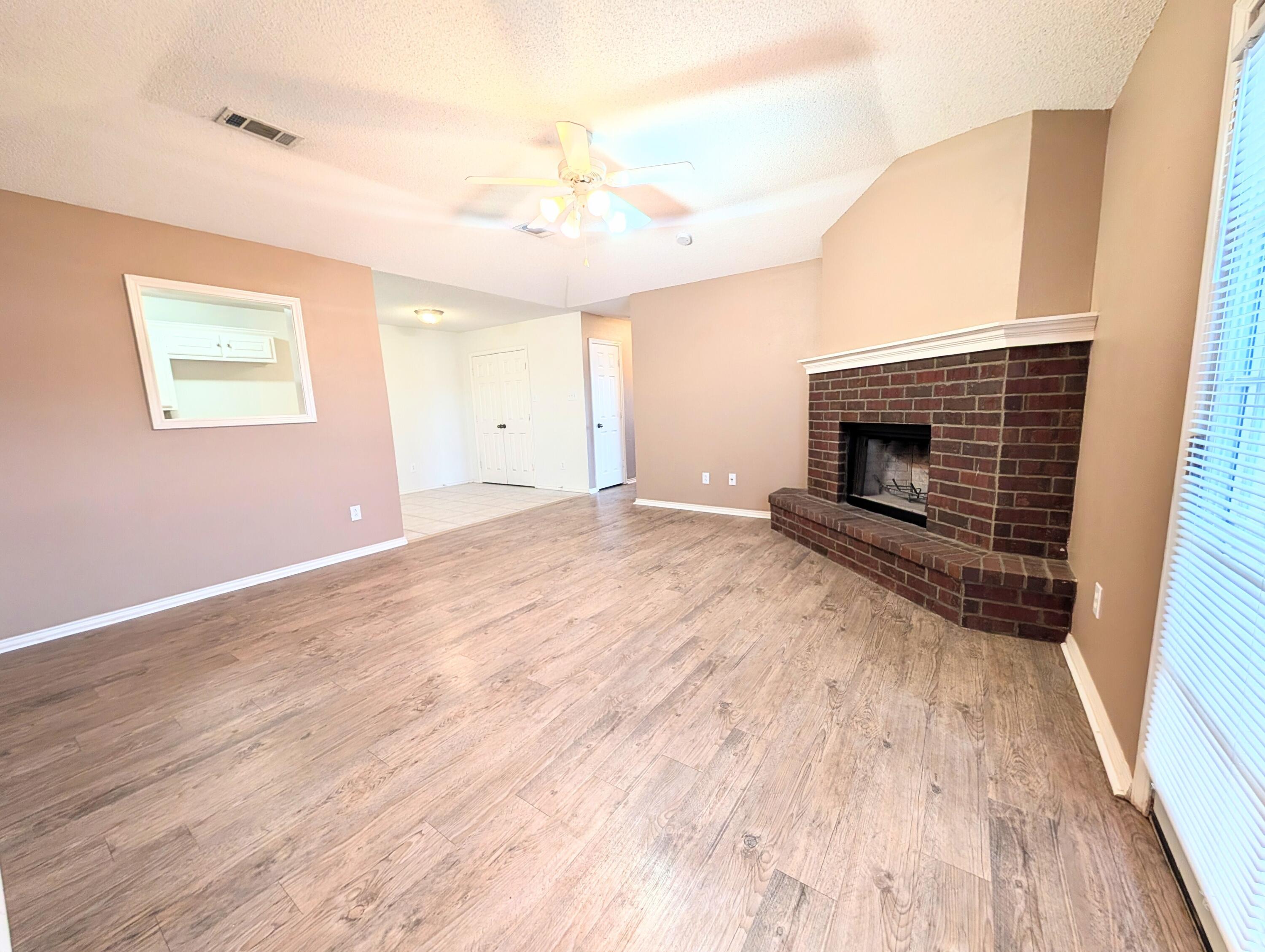 2417 87th Street, Unit B Lubbock, TX 79423 - Photo 2 of 11 a view of empty room with wooden floor and fireplace
