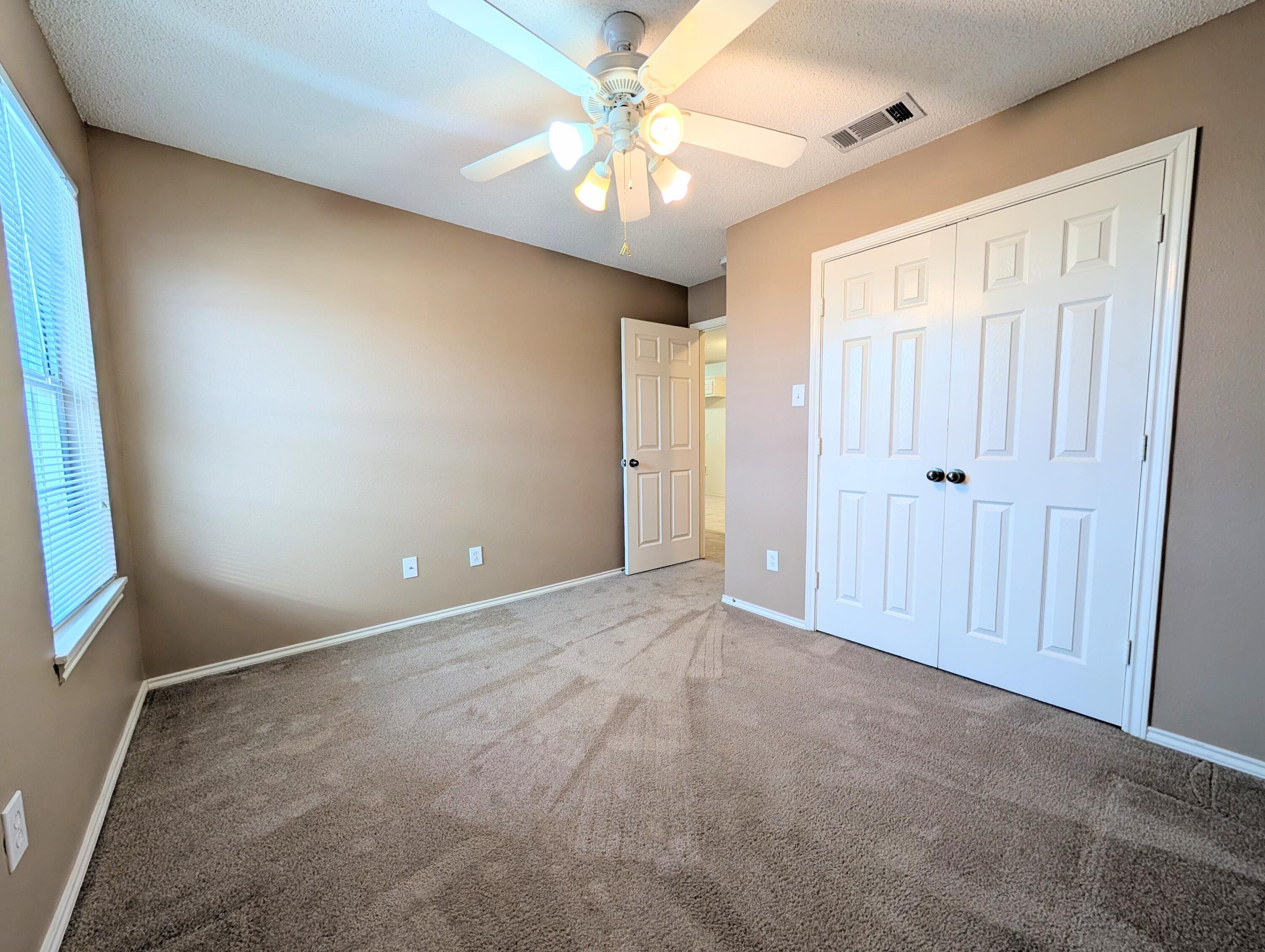 2417 87th Street, Unit B Lubbock, TX 79423 - Photo 3 of 11 an empty room with windows and fan