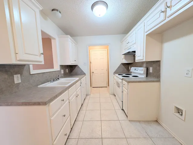 a kitchen with granite countertop white cabinets and white appliances