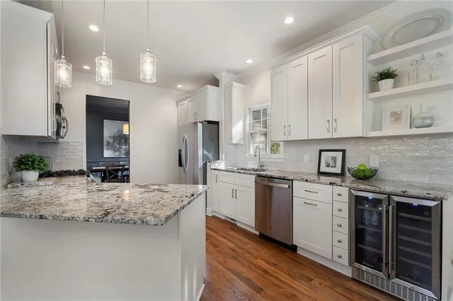 a kitchen with stainless steel appliances granite countertop a stove top oven a sink dishwasher a refrigerator and cabinets with wooden floor