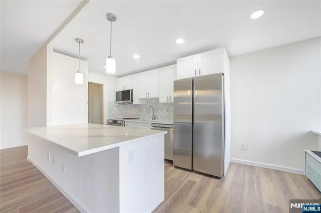 a kitchen with stainless steel appliances granite countertop a refrigerator a sink a stove and a wooden floors