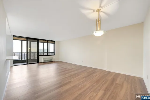 an empty room with wooden floor fan and windows