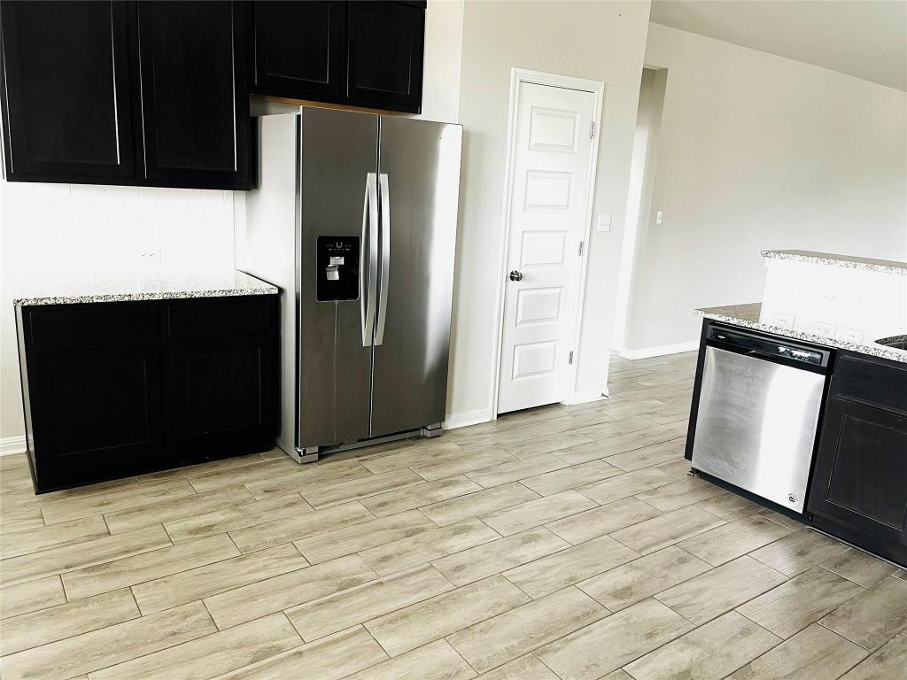 110 Trellis Boulevard Leander, TX 78641 - Photo 7 of 8 a view of a refrigerator in kitchen and an empty room with wooden floor